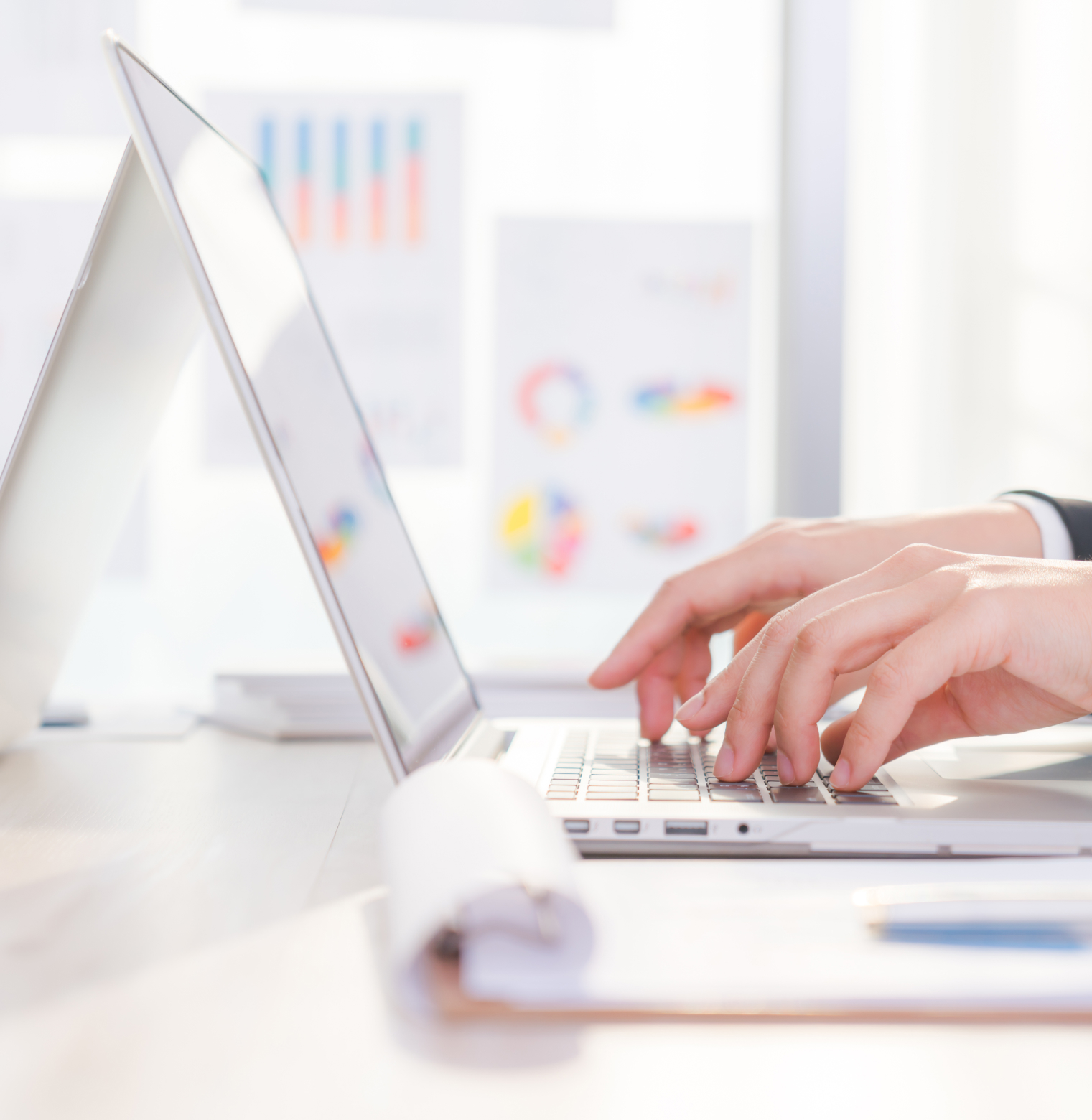 Person typing on a laptop with blurred business charts and graphs in the background0